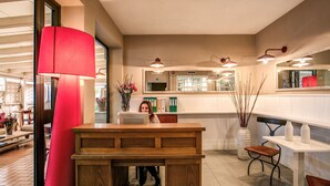 A modern kitchen with a wooden table, a red lamp, and a vase with flowers.