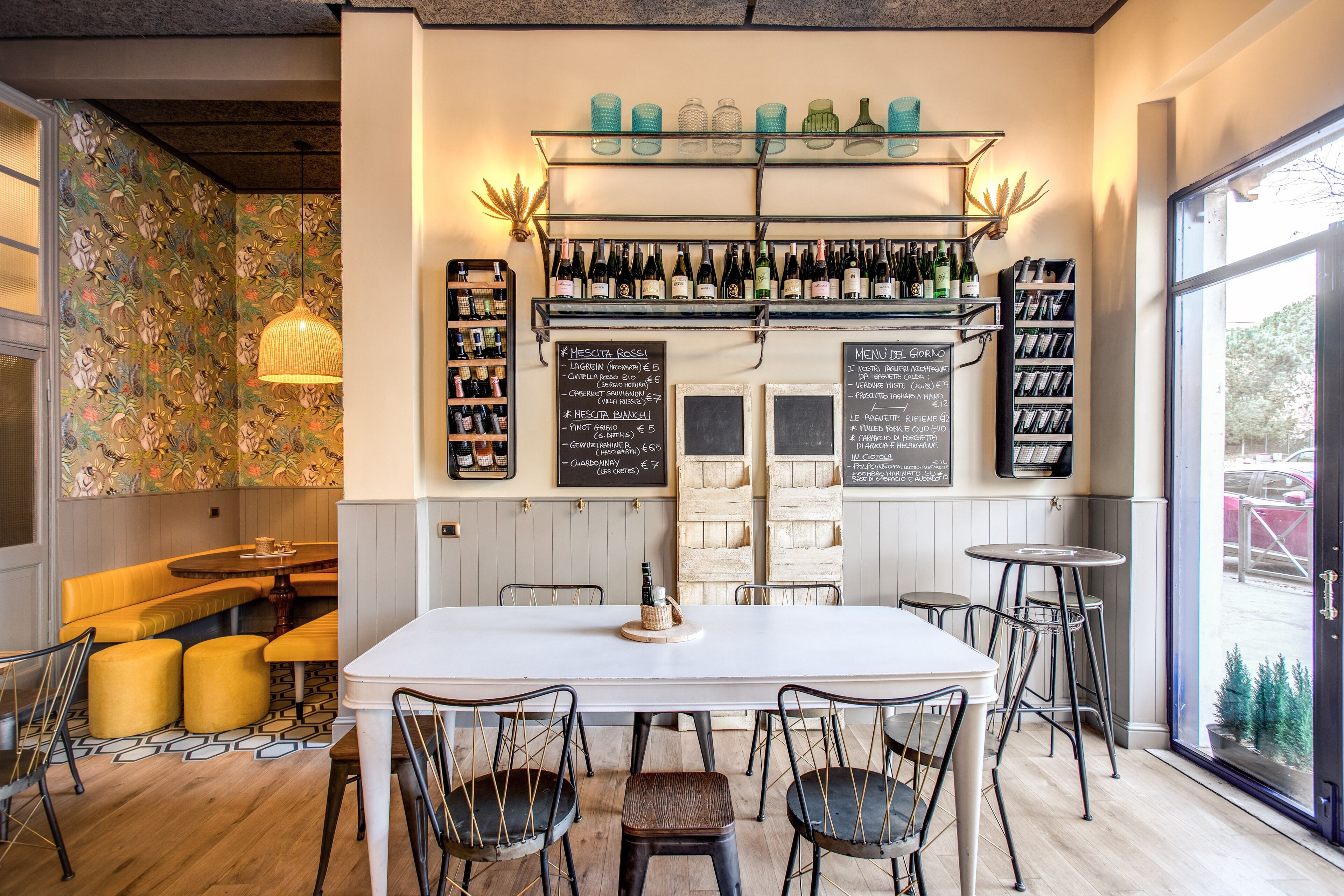 L’intérieur d’un restaurant présente un long comptoir, de nombreux tabourets et une variété de bouteilles de vin exposées sur des étagères.
