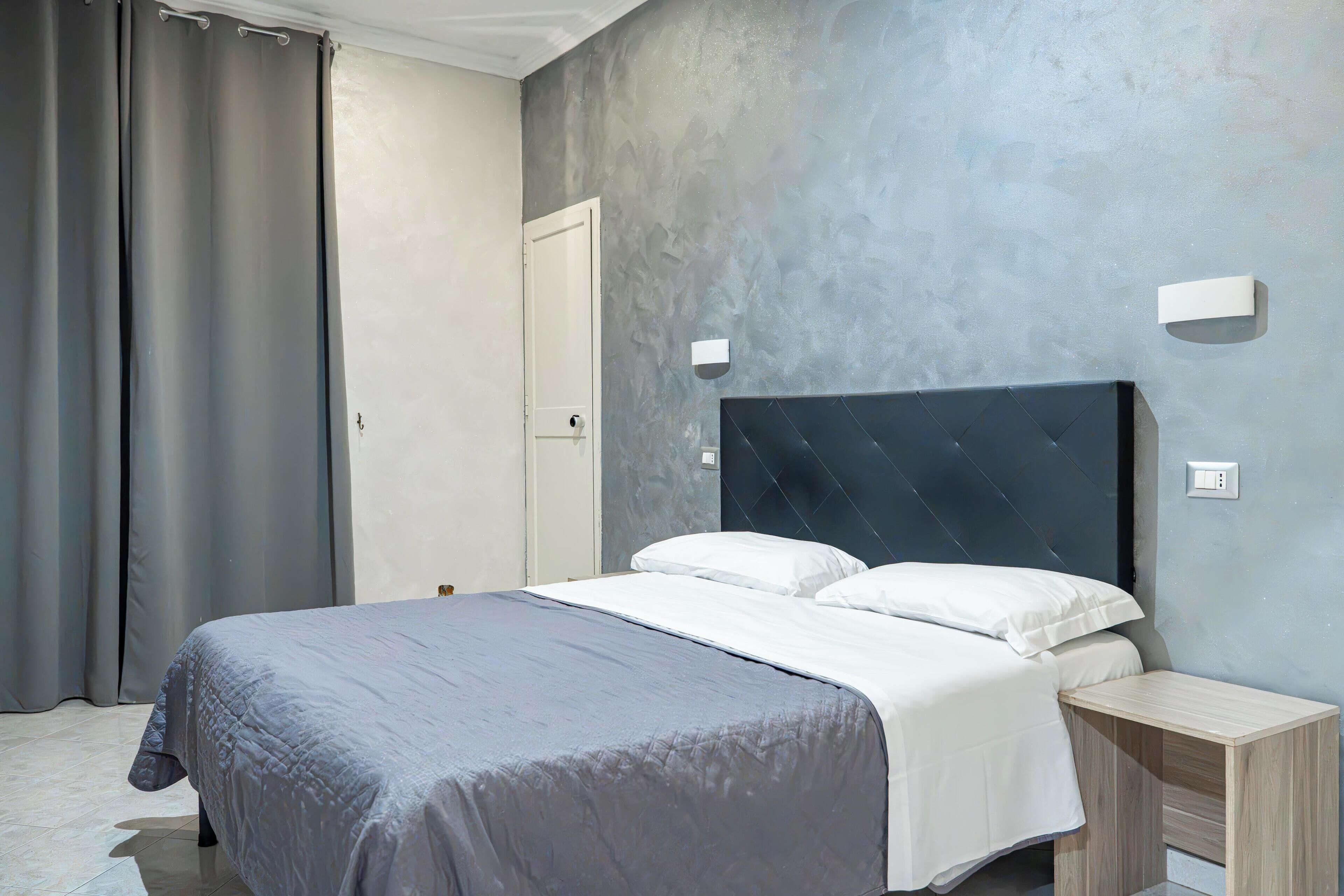 Un dormitorio con cama, mesita de noche, puerta y pared con textura.