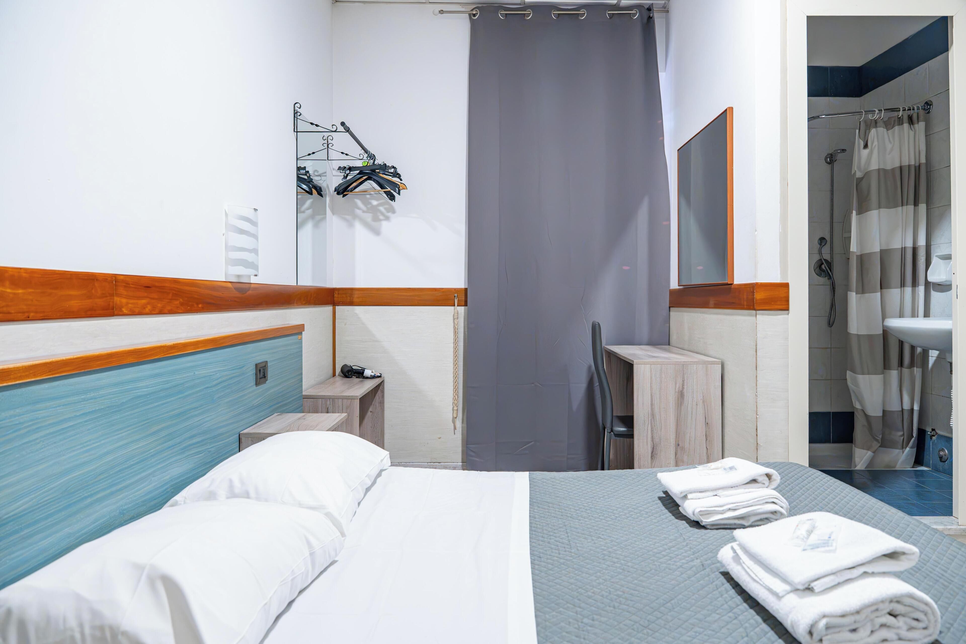 Hotellihuone, jossa on sänky, työpöytä, suihku ja kylpyhuone.