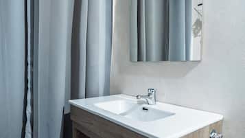 Ein Badezimmer mit einem weißen Waschbecken, einem Holfläschchen und einem Spiegel darüber.