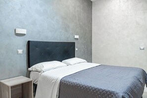 A modern bedroom with a bed, nightstands, and wall-mounted lights. - Hotel Planet (Rome)