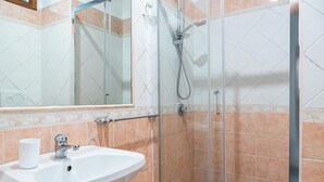 A bathroom with a white sink, a mirror, a shower with a handheld showerhead, and tiled walls. - Hotel Planet (Rome)