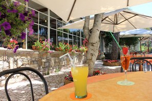 Een buitenzitgedeelte met tafels, stoelen en parasols.