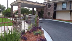 A building with a covered entrance, brick pillars, and a metal fence. - Gateway Inn - Savannah (Savannah)