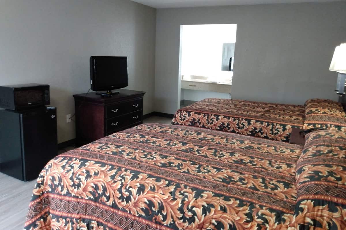 Une chambre d’hôtel avec un lit, un téléviseur posé sur une commode et une fenêtre donnant sur l’extérieur.