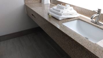 Une salle de bain avec un comptoir en granit, un lavabo blanc et un distributeur de serviettes.