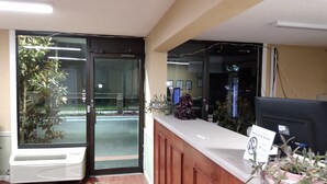 A reception desk with a computer monitor, a sign, and a potted plant. - Gateway Inn - Savannah (Savannah)