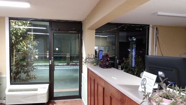 A reception desk with a computer monitor, a sign, and a potted plant. - Gateway Inn - Savannah (Savannah)