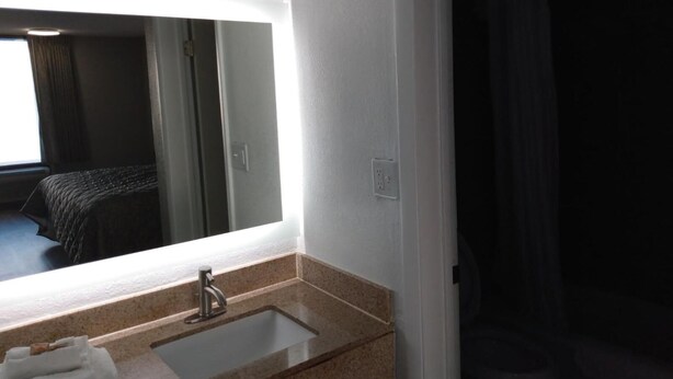 A hotel bathroom with a large mirror, a sink, and a toilet. - Gateway Inn - Savannah (Savannah)