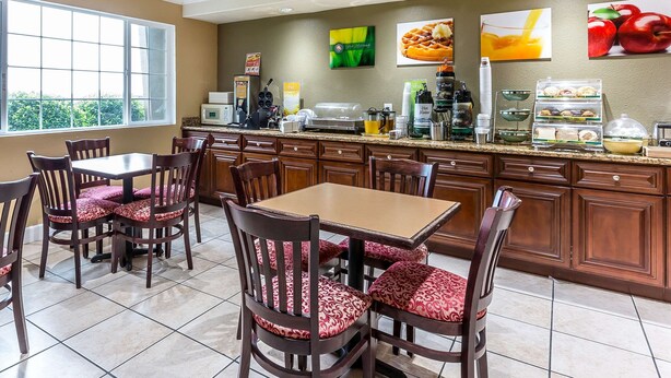 A hotel kitchen with a dining area, equipped with a coffee machine, tea station, and various food items. - Quality Inn near Hearst Castle (San Simeon)