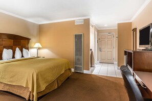 A hotel room with a bed, a desk, a television, and a door leading to a bathroom. - Quality Inn near Hearst Castle (San Simeon)