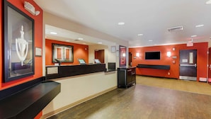 A hotel reception area with a black reception desk, a framed sculpture, and a large window. - Extended Stay America Suites Los Angeles Simi Valley (Simi Valley)