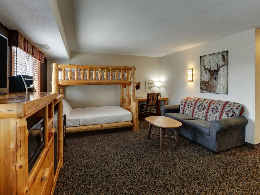 A cozy room with a bunk bed, a sofa, a small table, and a television.