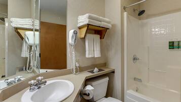 Un baño con lavamanos, espejo, toallero y zona de ducha.