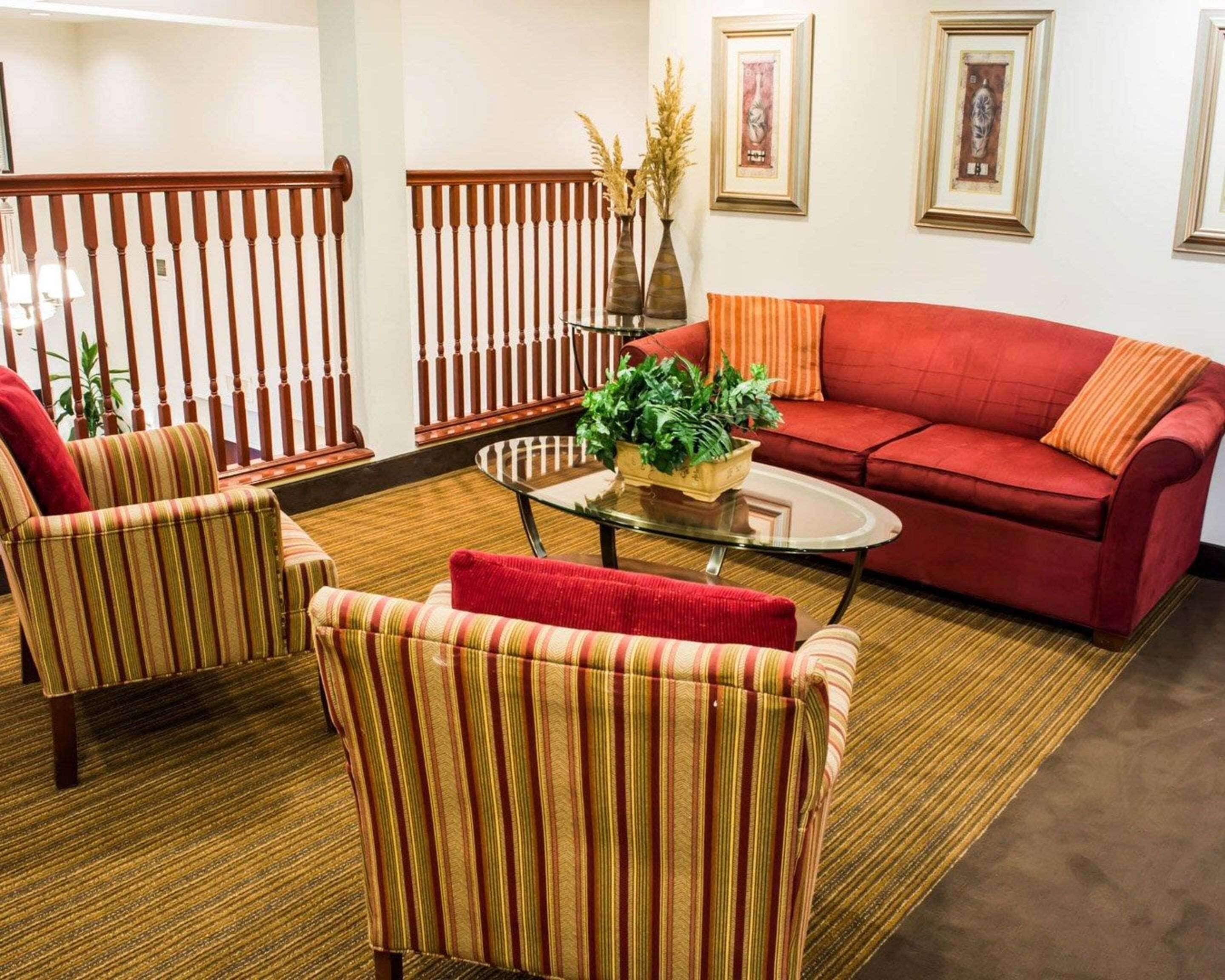 Una sala de estar con sillones a rayas, un sofá rojo y una mesa de centro de vidrio.