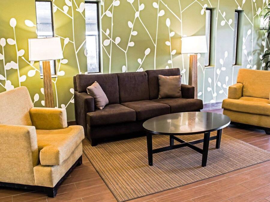 Una sala de estar moderna con un sofá marrón, dos sillones y una mesa de centro.