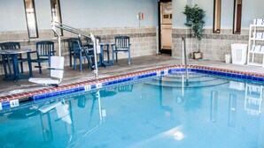 A swimming pool with a tiled edge, a lifeguard stand, and a few chairs and tables around the pool area. - Sleep Inn & Suites Virginia Horse Center (Lexington)