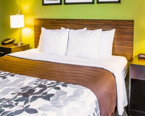 A hotel room with a neatly made bed, a bedside lamp, a telephone, and a nightstand.