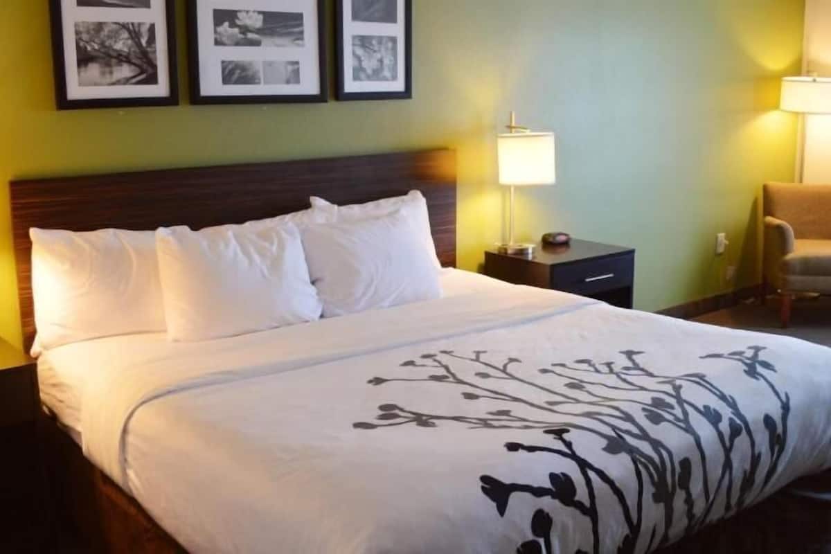 A hotel room with a large bed, two bedside tables, a chair, and framed pictures on the wall.