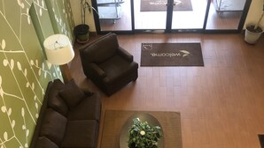 A lobby with a sectional sofa, a round coffee table with a plant, a small side table, and a reception desk. - Sleep Inn & Suites Virginia Horse Center (Lexington)