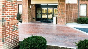 A building entrance with a brick facade, a covered walkway, and a glass door. - Sleep Inn & Suites Virginia Horse Center (Lexington)
