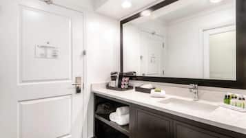 A modern bathroom with a white sink, dark cabinets, a large mirror, and an emergency exit plan on the door.
