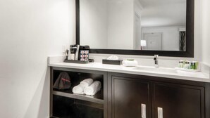 A modern bathroom with a large mirror, a white sink, and a towel rack. - Aggie Inn, an Ascend Collection Hotel (Davis)