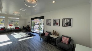 A spacious lobby with a modern design, featuring a reception desk, seating area, and artwork on the walls. - Aggie Inn, an Ascend Collection Hotel (Davis)