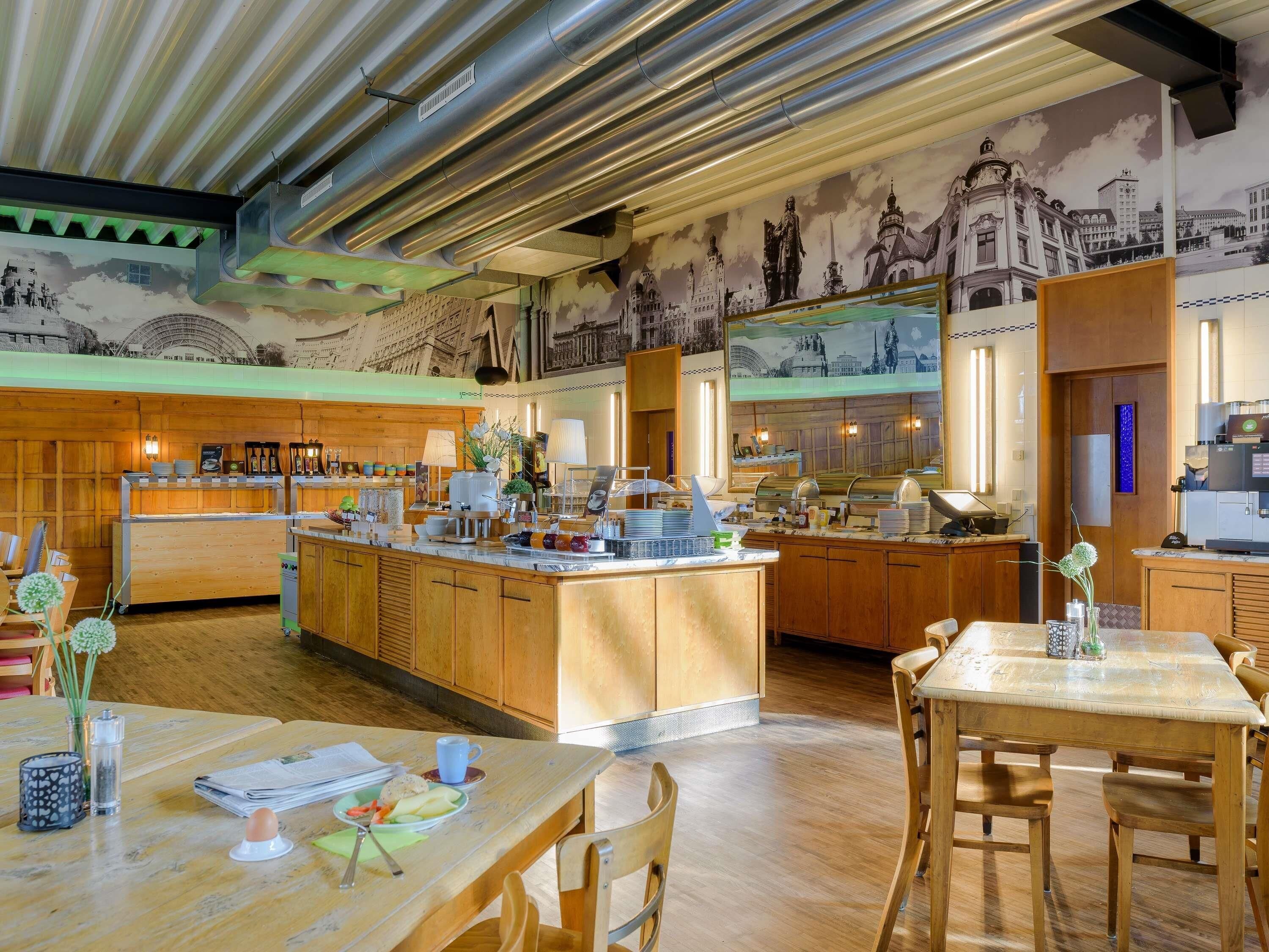 A modern kitchen with a central island, wooden cabinets, and a mural of cityscapes on the wall.