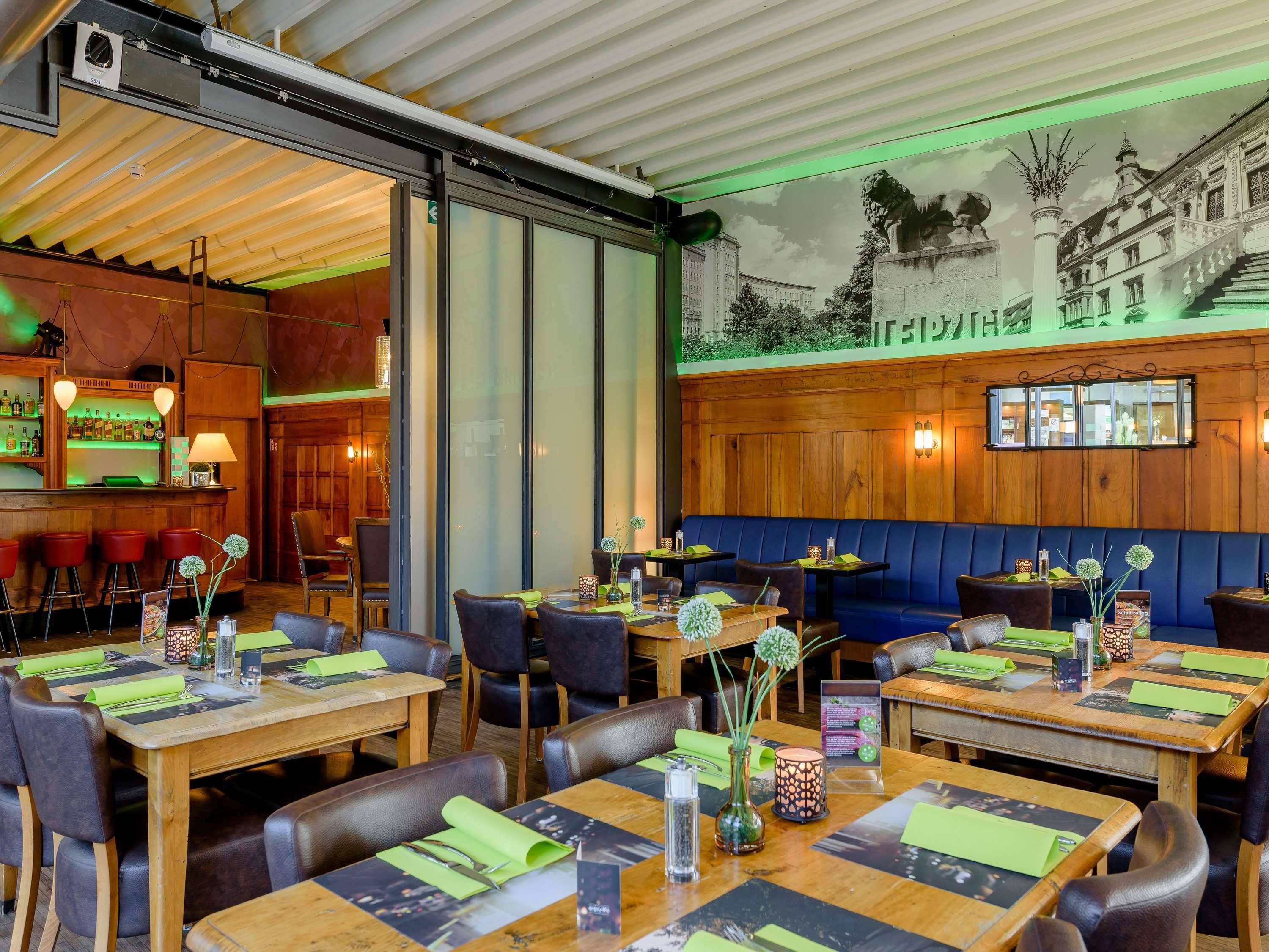 Un restaurante con mesas de madera, cabinas y un mural de un edificio en la pared.