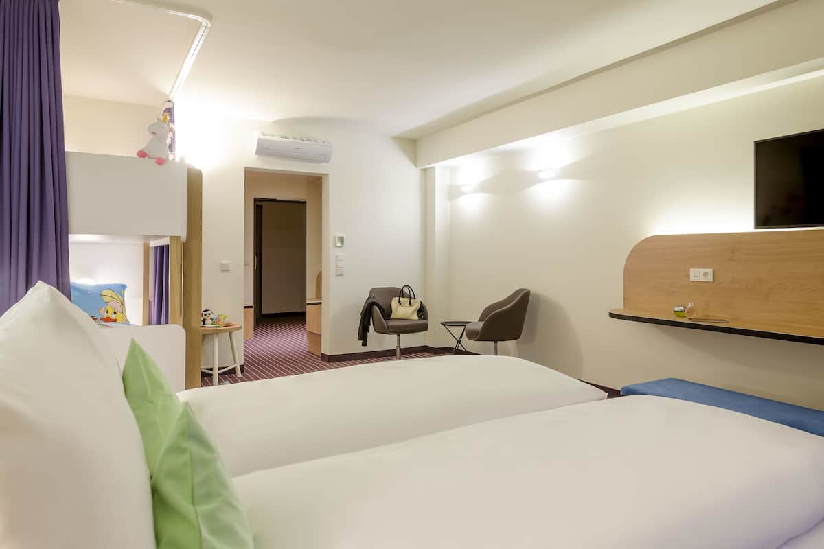 Une chambre d’hôtel avec deux lits, un bureau, une chaise, une télévision et une armoire.