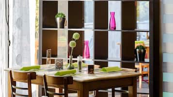 A dining area with a wooden table, chairs, and a decorative shelf with potted plants.