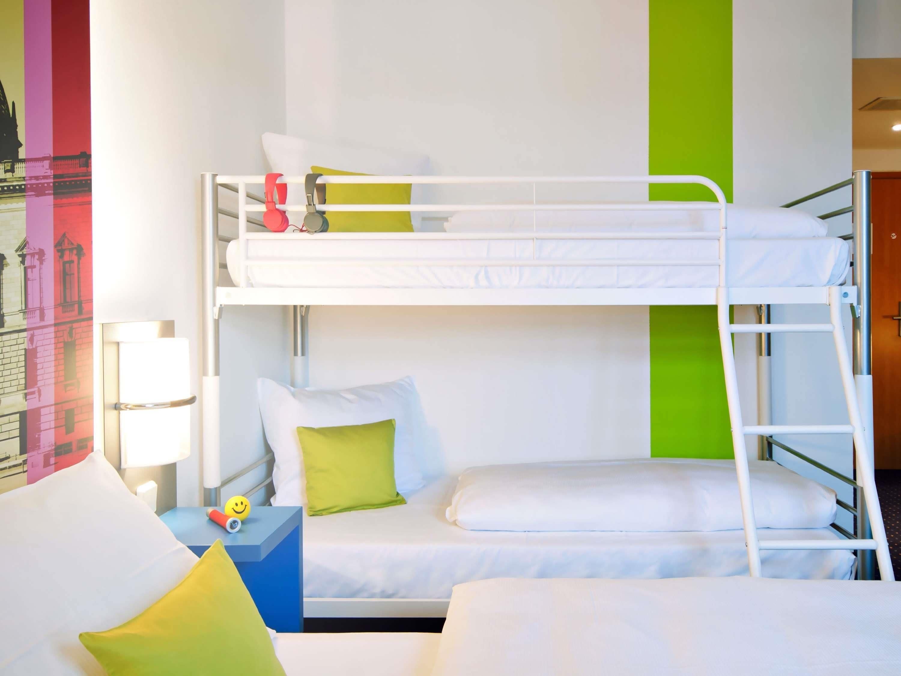 Dormitorio con literas, almohadas, una mesita de noche y una obra de arte en la pared.