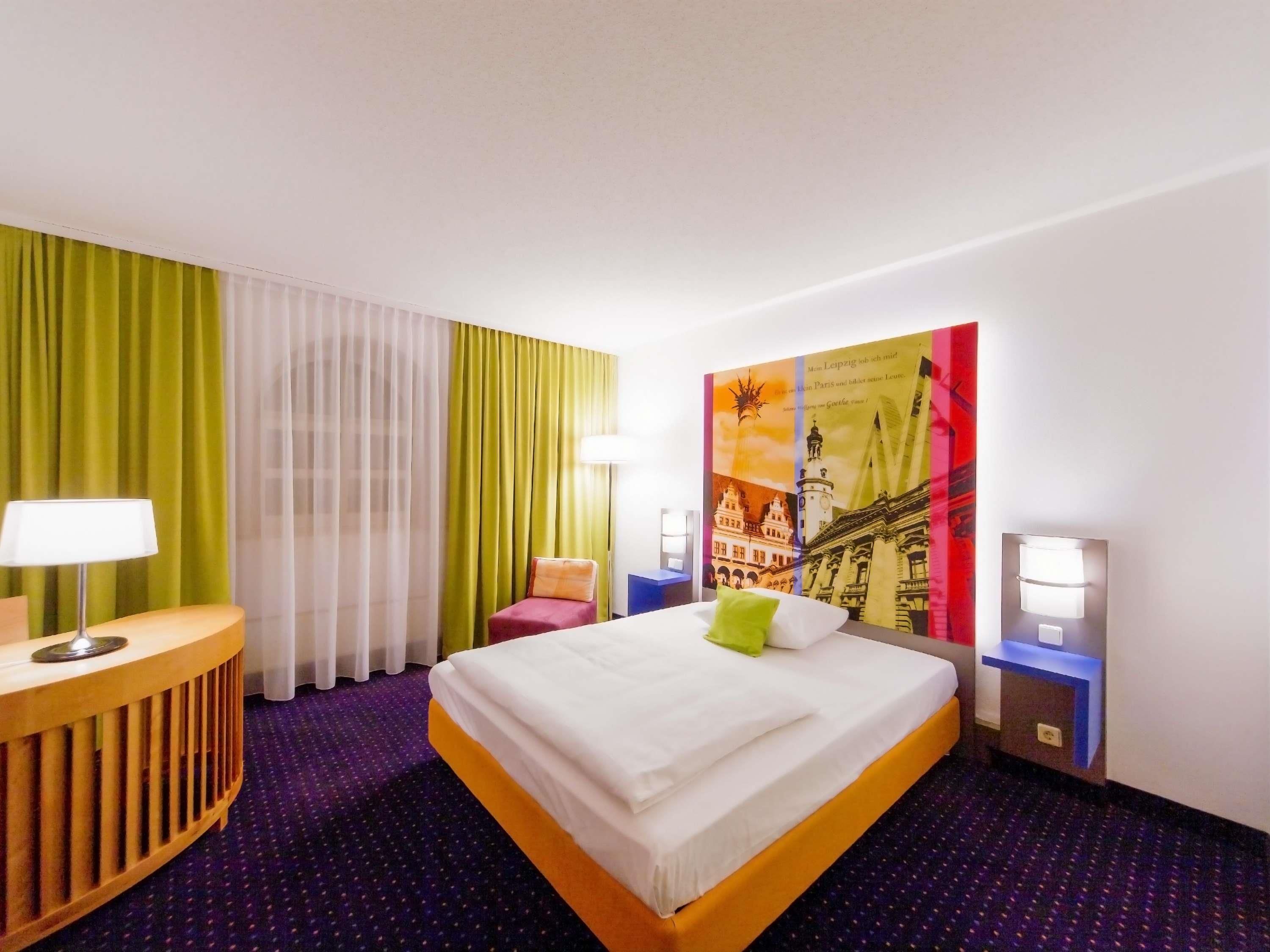 Habitación de hotel con una cama, un escritorio, una silla y un cartel en la pared.