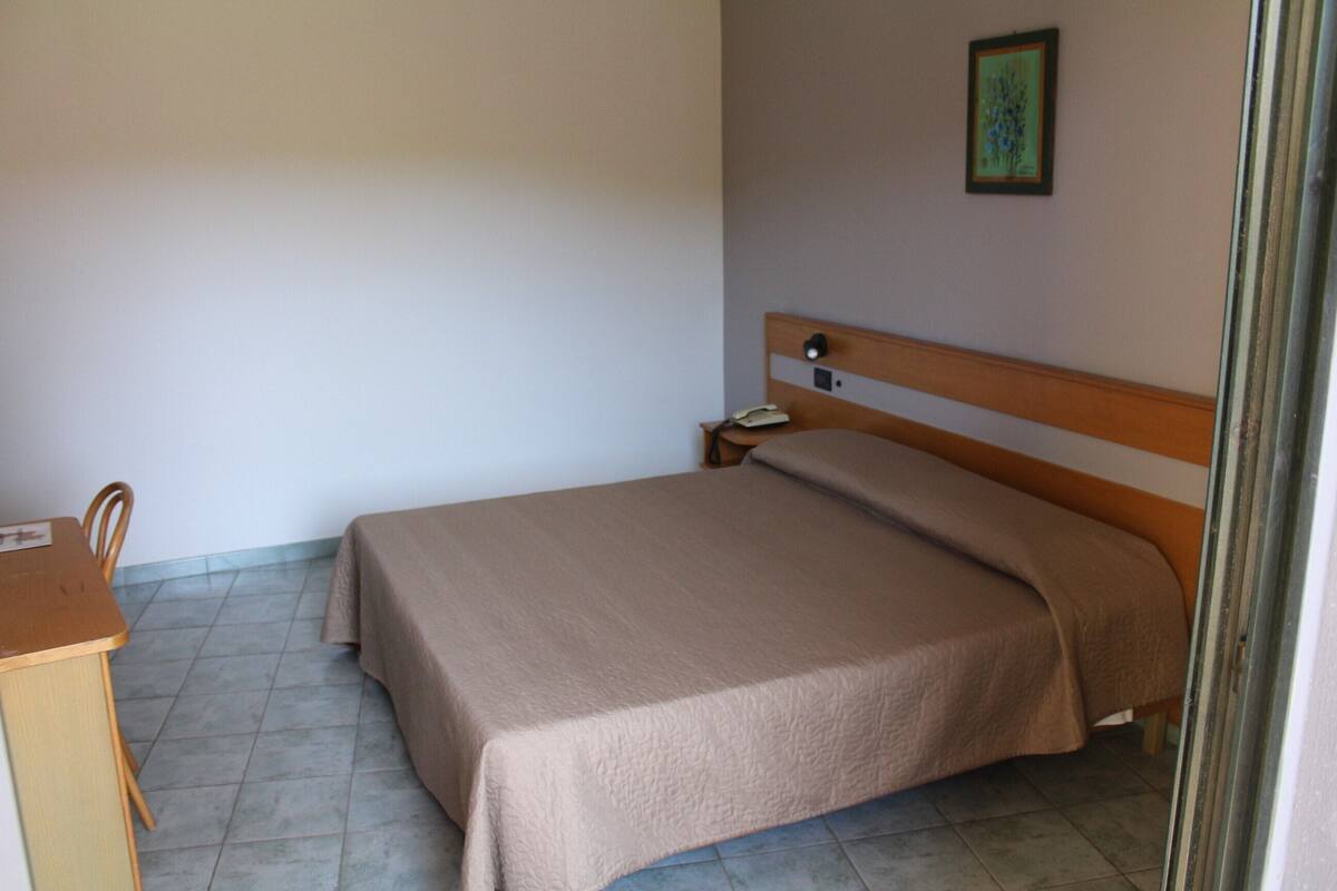 A single bed with a wooden headboard in a room with a tiled floor.
