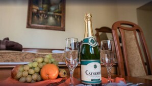 A bottle of Catherine wine, two empty glasses, a bunch of grapes, and an orange on a table. - City Hotel Unio Superior (Budapest)