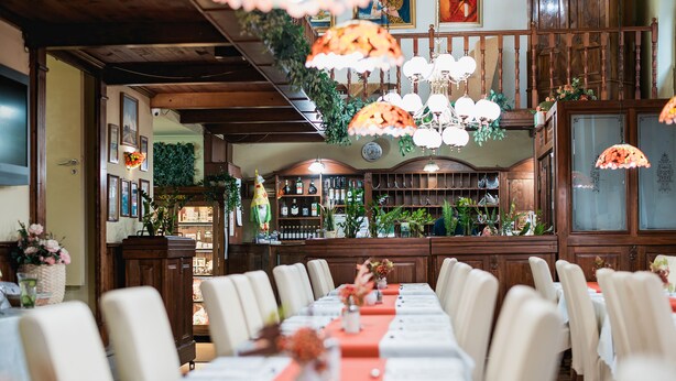 A long dining table with white chairs, a red table runner, and hanging lamps. - City Hotel Unio Superior (Budapest)