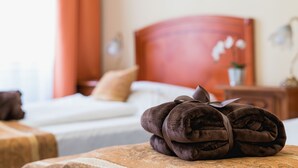 A neatly made bed with a brown headboard, a rolled-up towel, and a wooden nightstand with a lamp. - City Hotel Unio Superior (Budapest)