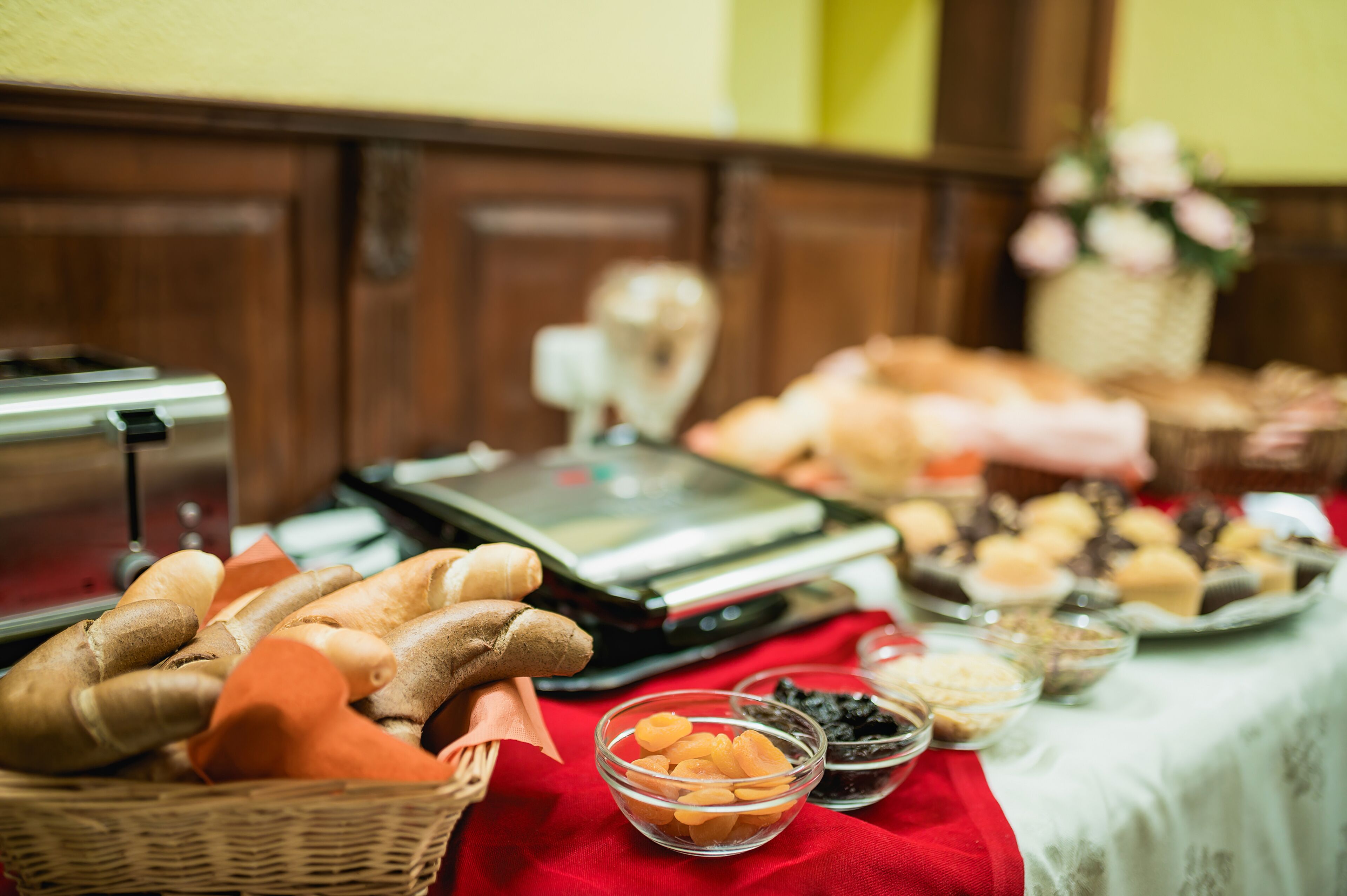 A buffet table with various food items, including bread, pastries, and bowls of fruit and nuts.