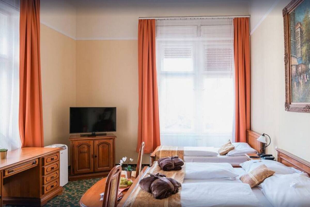 A hotel room with two beds, a television, a desk with drawers, a cabinet, and a painting on the wall.