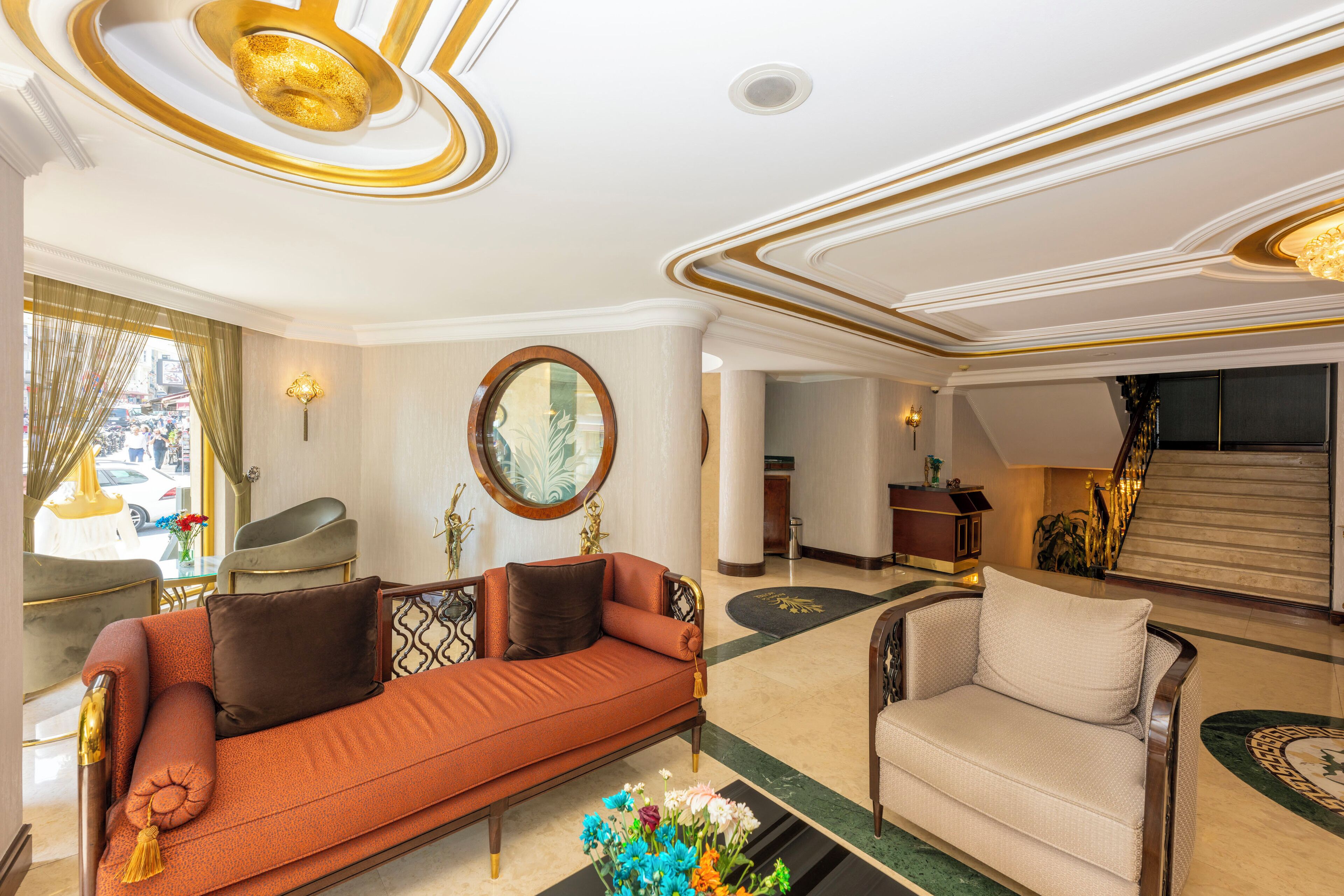 A spacious lobby with a sofa, armchairs, and a staircase.