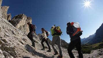 A group of hikers on a rocky mountain trail with a clear sky.