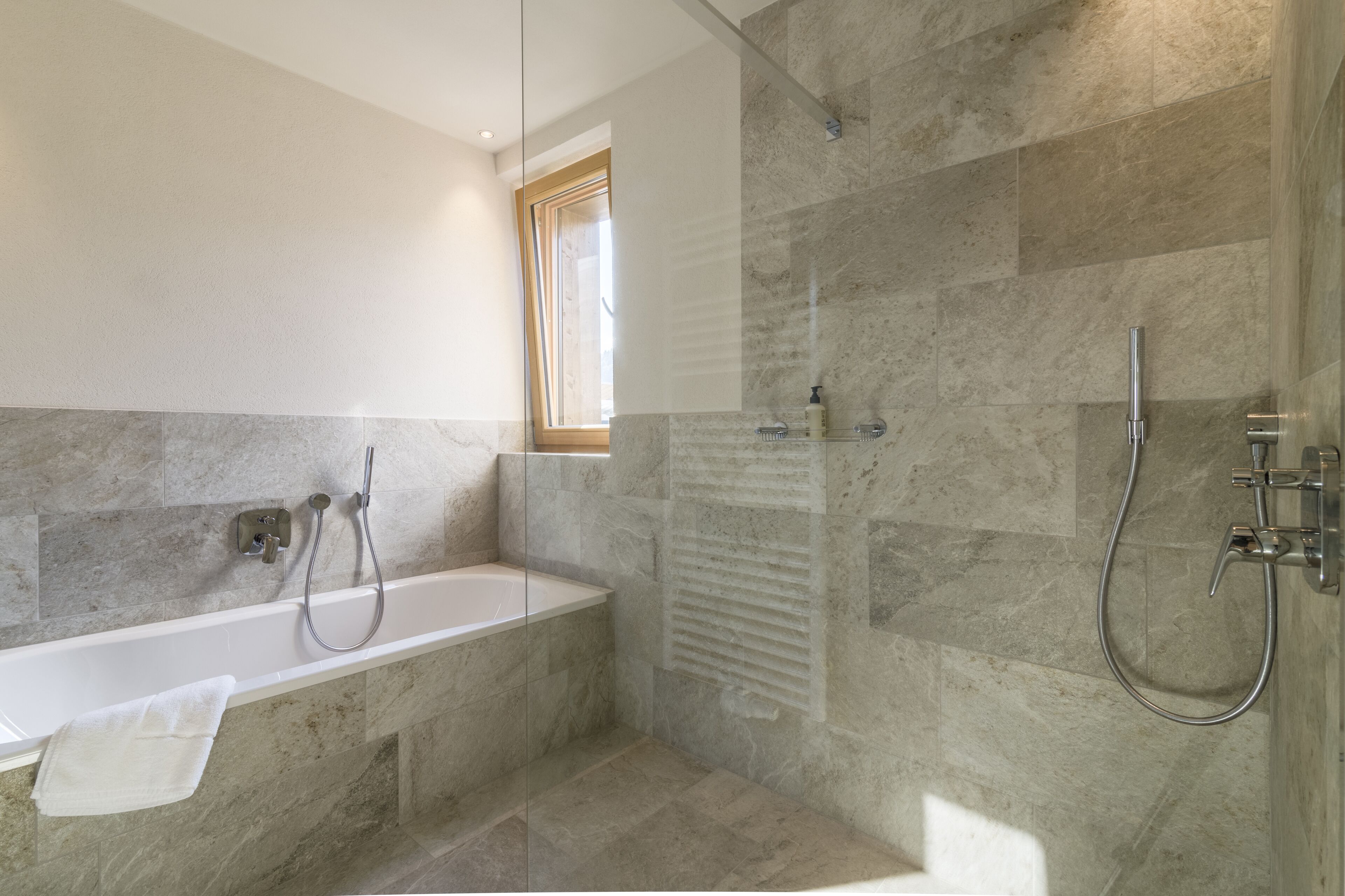 A modern bathroom with a bathtub, shower, and glass-enclosed shower area.