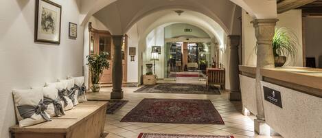 A hotel lobby with a wooden bench, a reception desk, and a red patterned rug.
