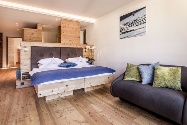Un dormitorio con una cama de madera, un sofá oscuro y un cuadro en la pared.