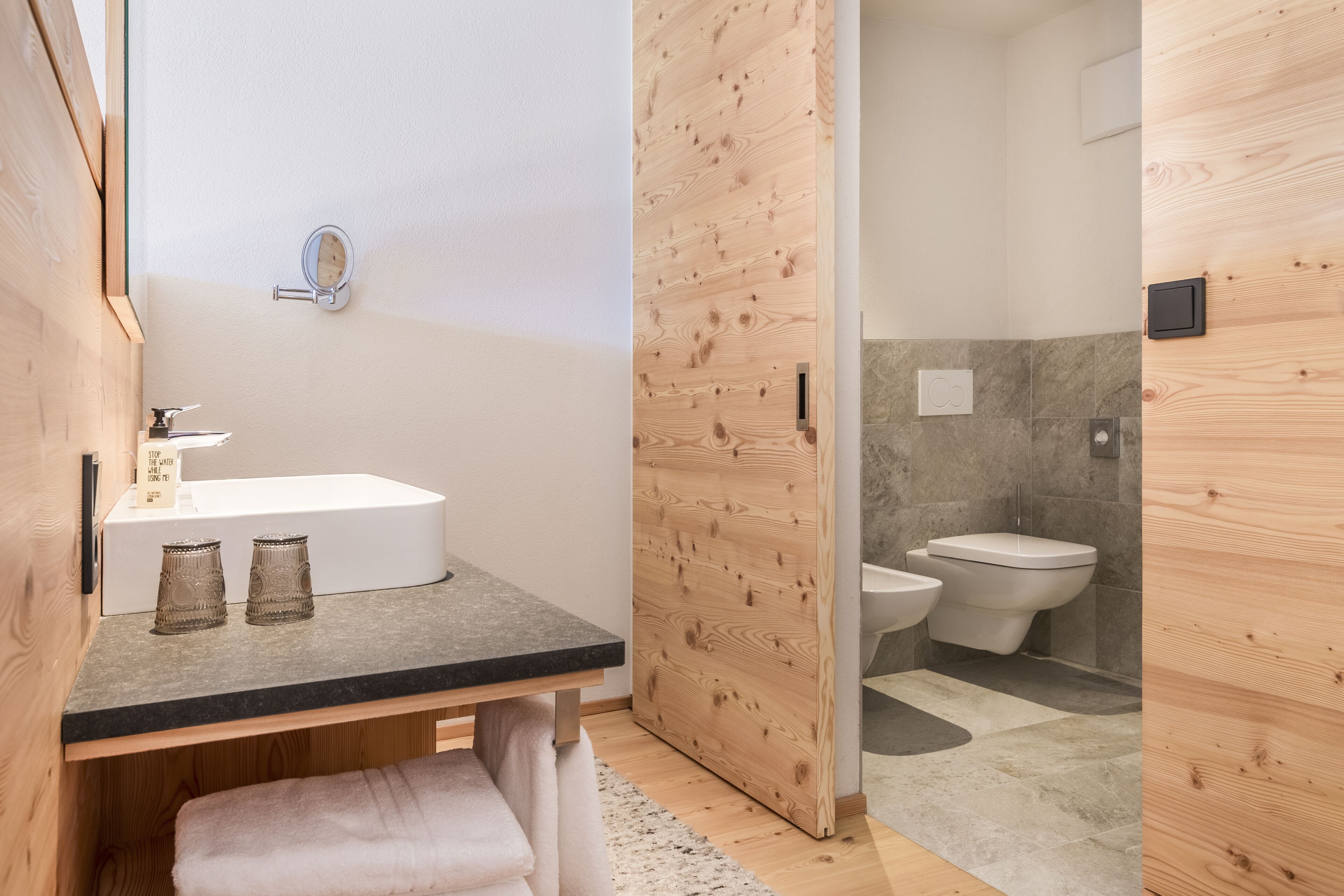 Een moderne badkamer met een houten wastafelmeubel, een wastafel en een toilet.