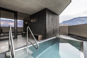 A modern indoor pool with a clear view of mountains in the background. - Hotel Langgenhof (Brunico)