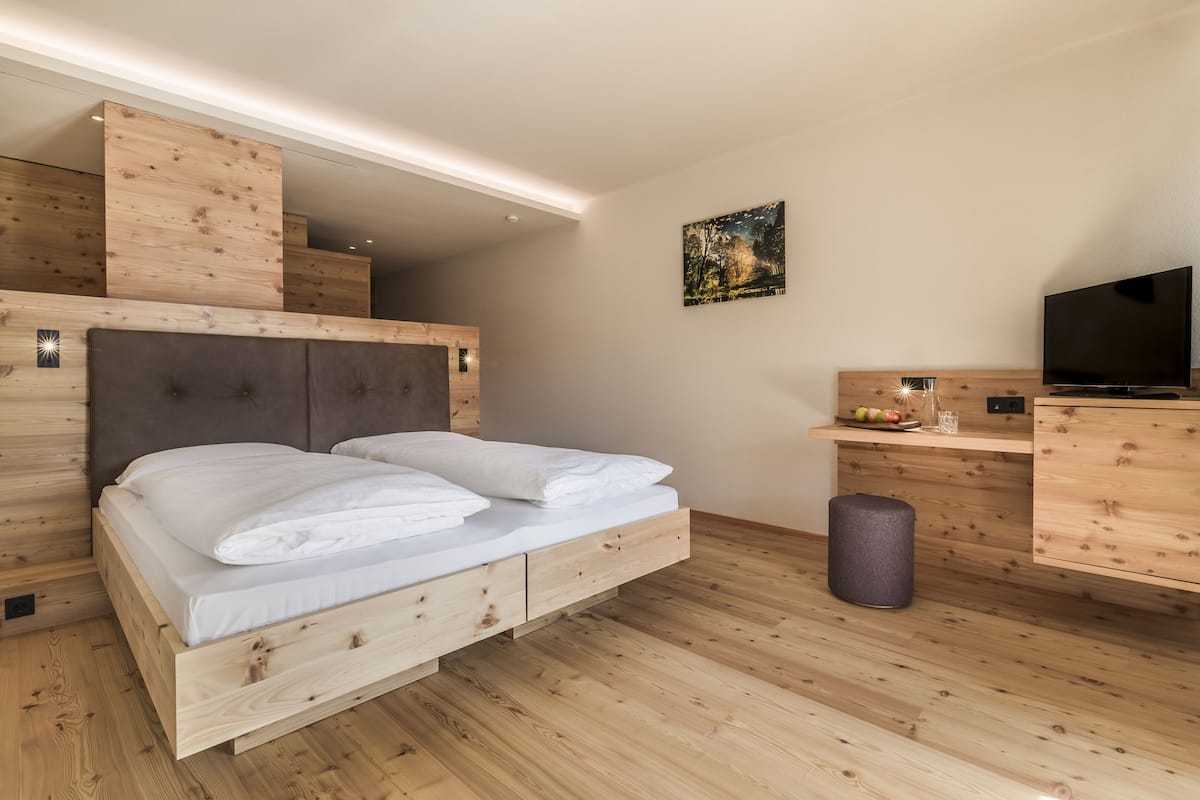 A modern bedroom with a wooden bed, a TV, and a small desk area.