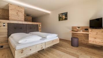 A modern bedroom with a wooden bed, a TV, and a small desk area.